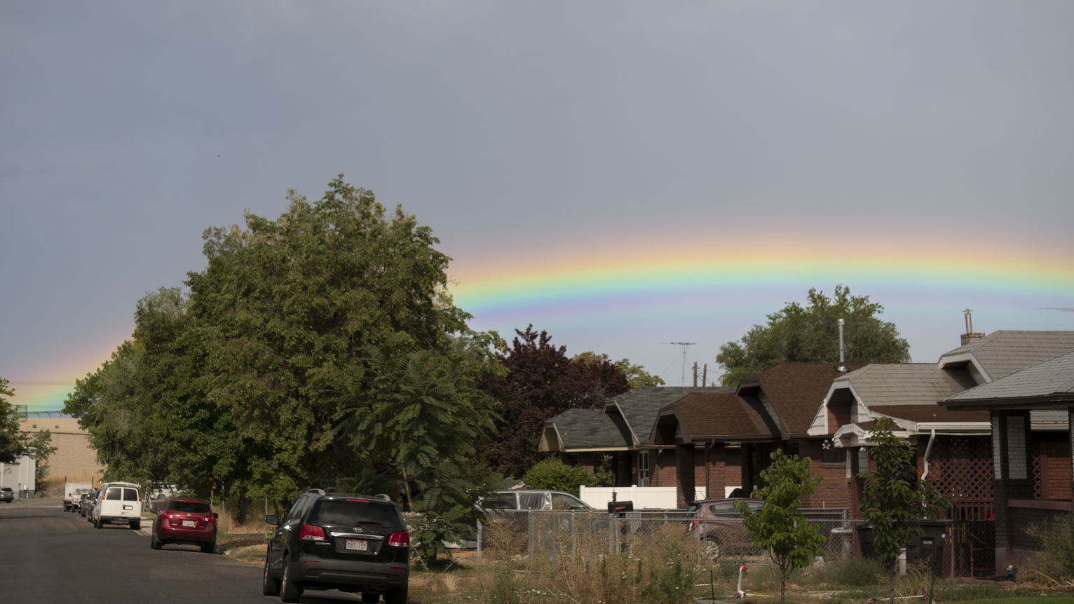 Behind neighborhood homes a bright rainbow